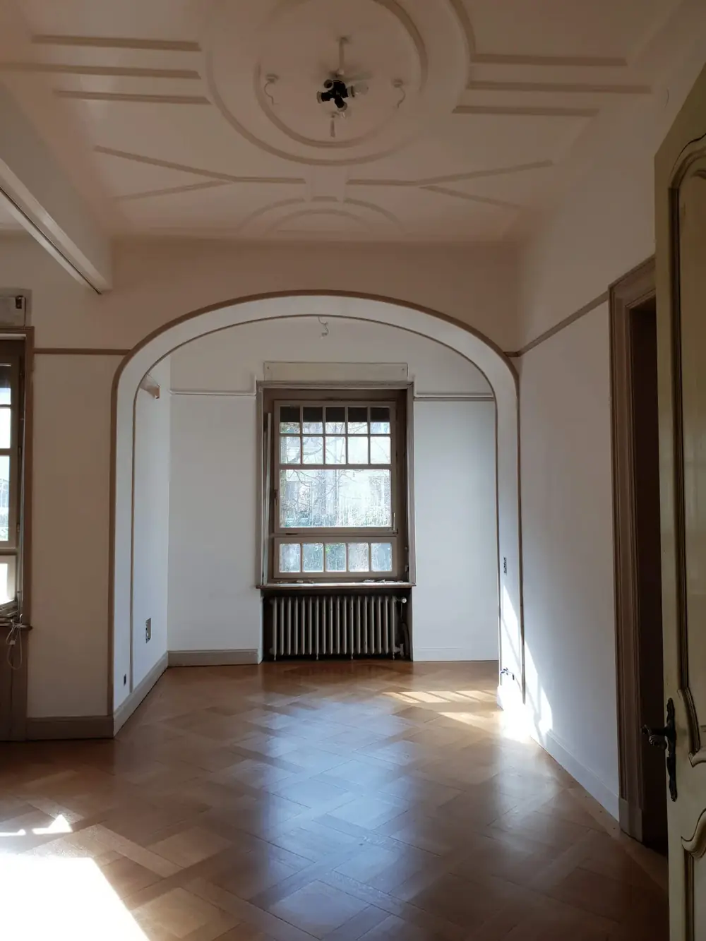 Renovierter Altbauraum mit Rundbogen, Deckenrosette und Parkett – Kreativ Maler